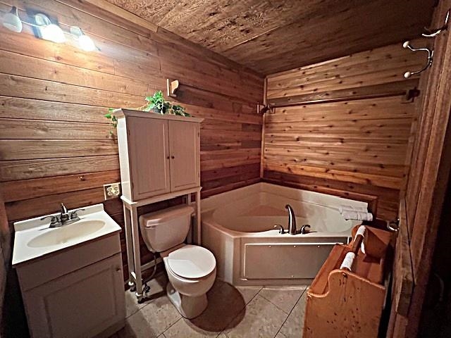 Wood-paneled bathroom with a corner bathtub, toilet, and white-sink vanity.