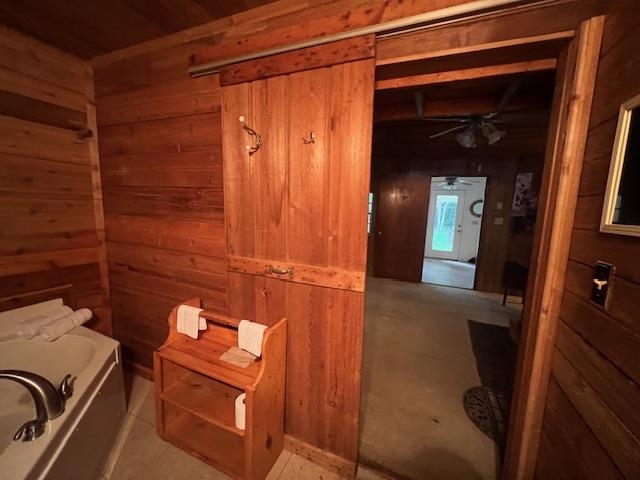 Wood-paneled bathroom with a bathtub, towel bench, and open doorway.