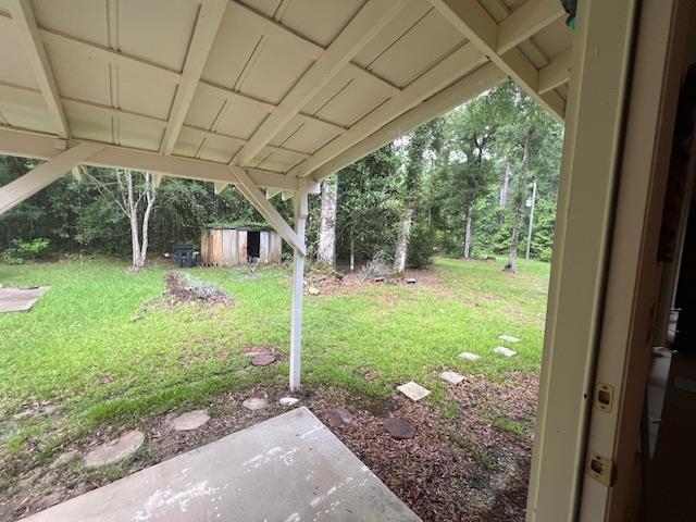 Covered patio overlooking a grassy, tree-lined backyard with a small shed.