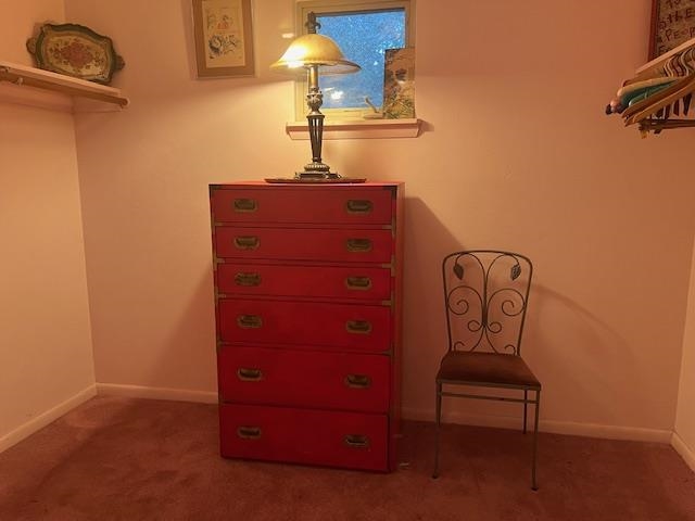 Interior with a tall red chest of drawers, a metal chair, and clothes hanging at the side.