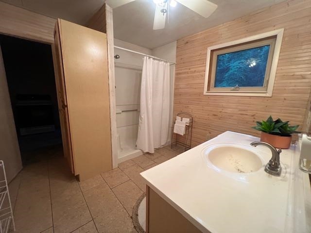 Bathroom with a white vanity, curtained shower, wood-paneled walls, and a small window.
