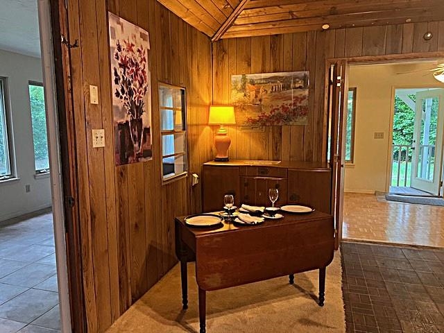 Wood-paneled dining area with a set table, sideboard, and vaulted ceiling.