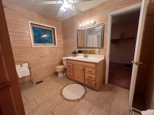 Bathroom with wood-paneled walls, tiled floor, and a wood vanity beneath a framed mirror.