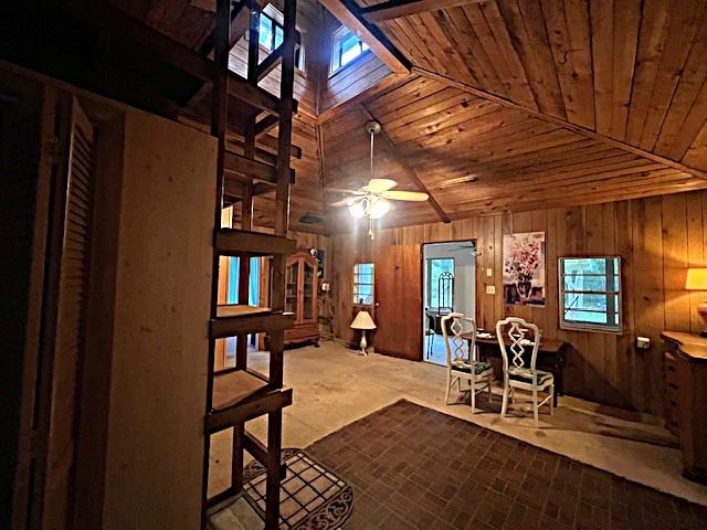 Wood-paneled living and dining area with a vaulted ceiling and loft ladder.