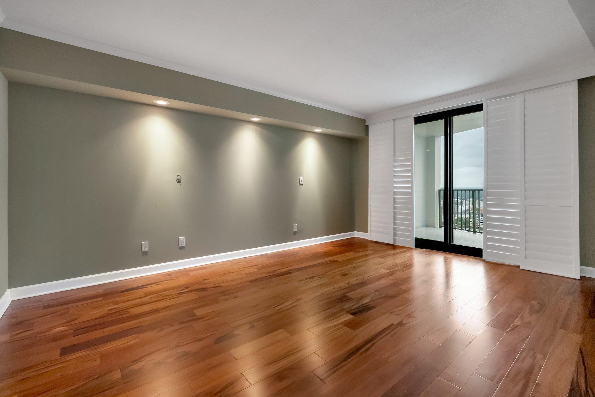 Empty living room with hardwood floors and sliding doors to a balcony.