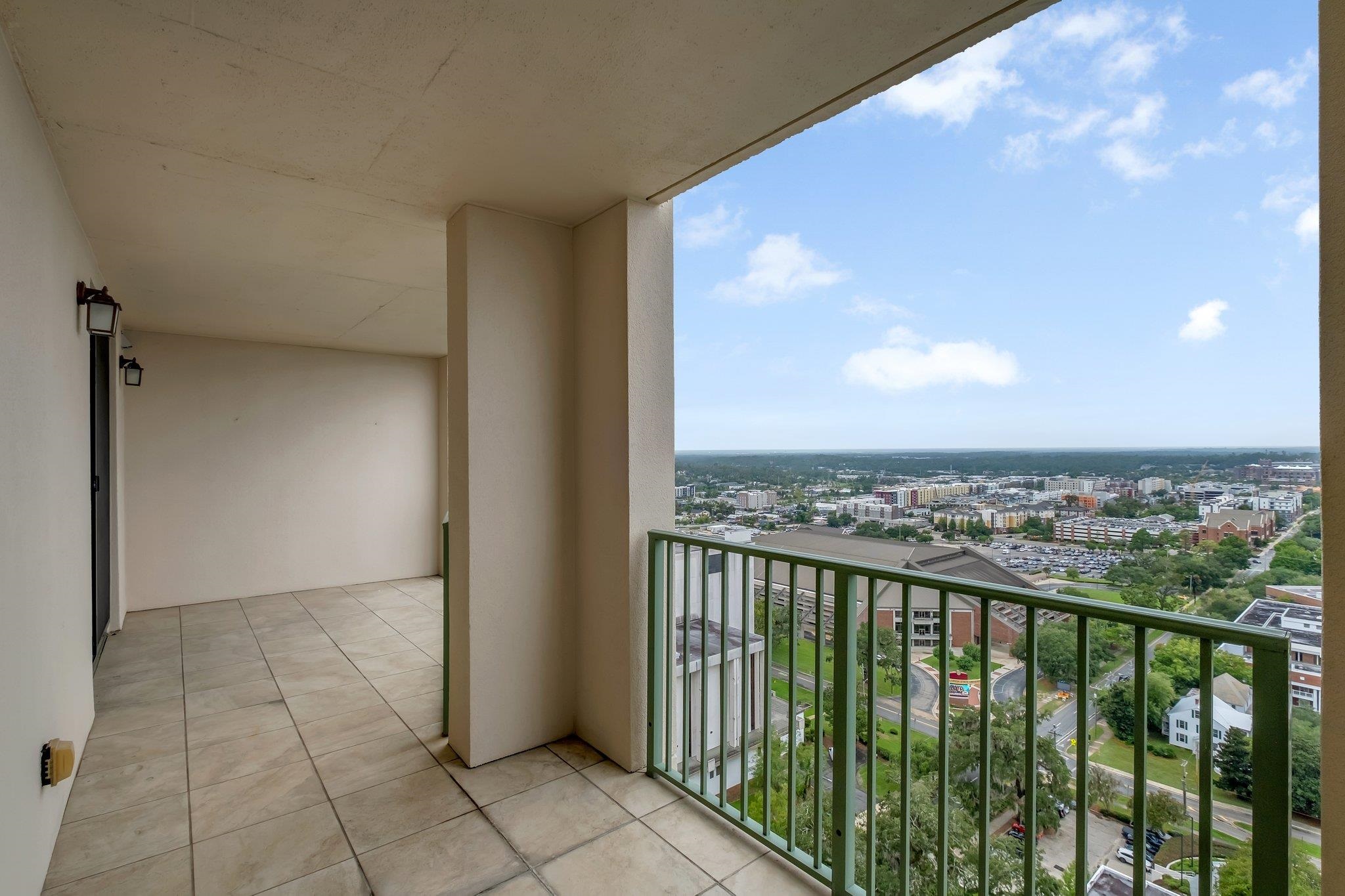 Covered tiled balcony overlooks downtown Tallahassee, with green railings and a wide city view.