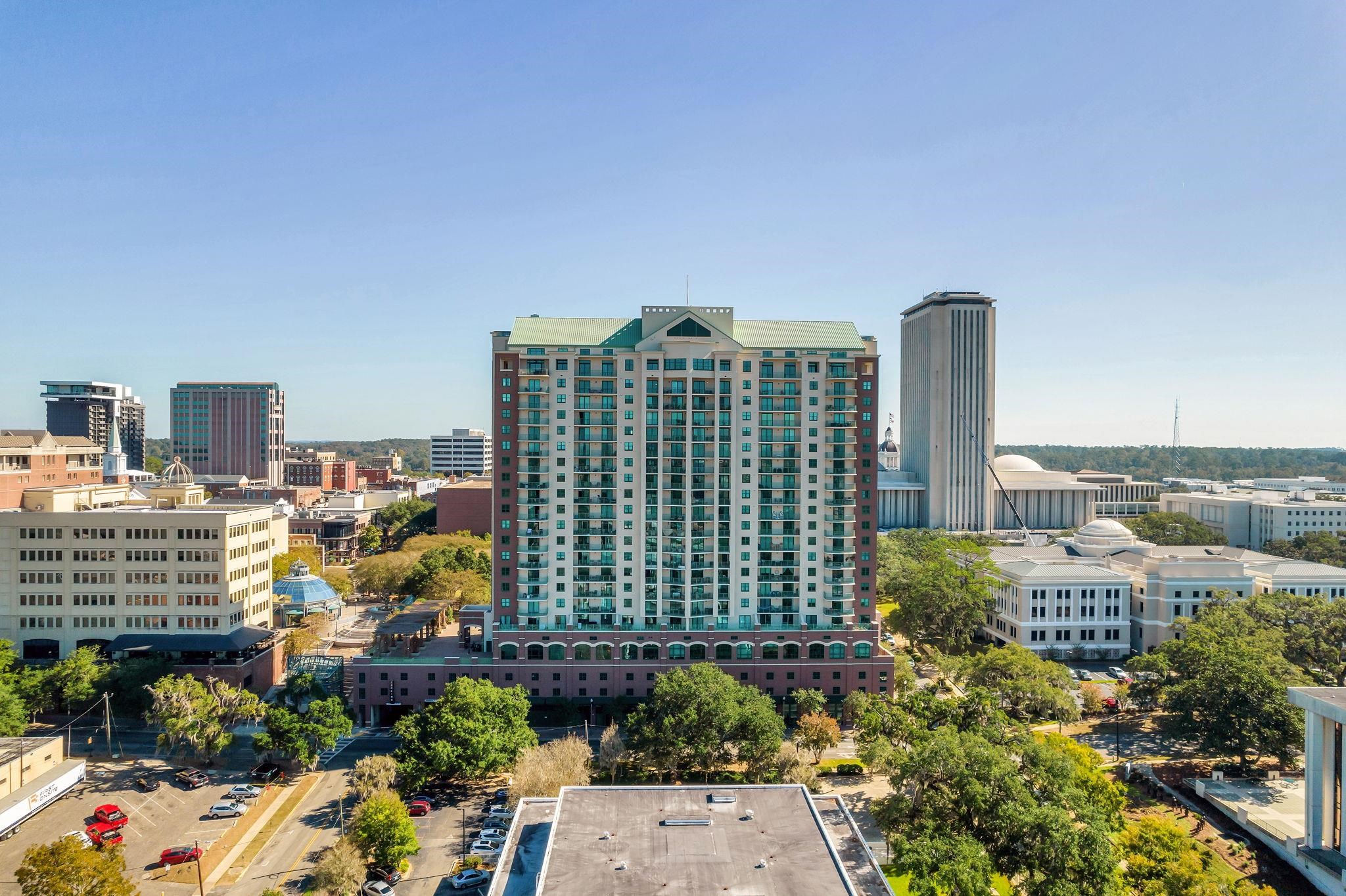 High-rise condominium with a green roof and balconies among downtown Tallahassee buildings.