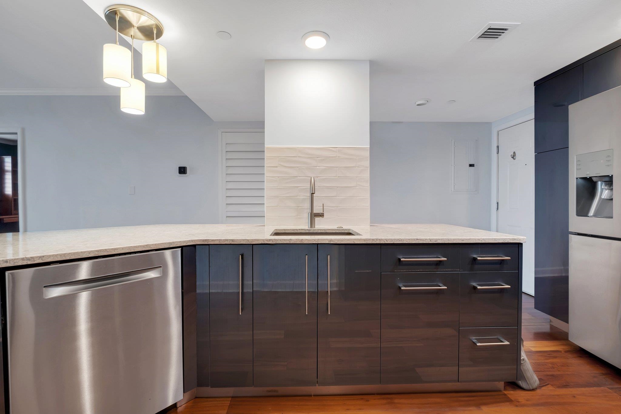 Modern kitchen with a large island, dark cabinetry, and stainless steel appliances.