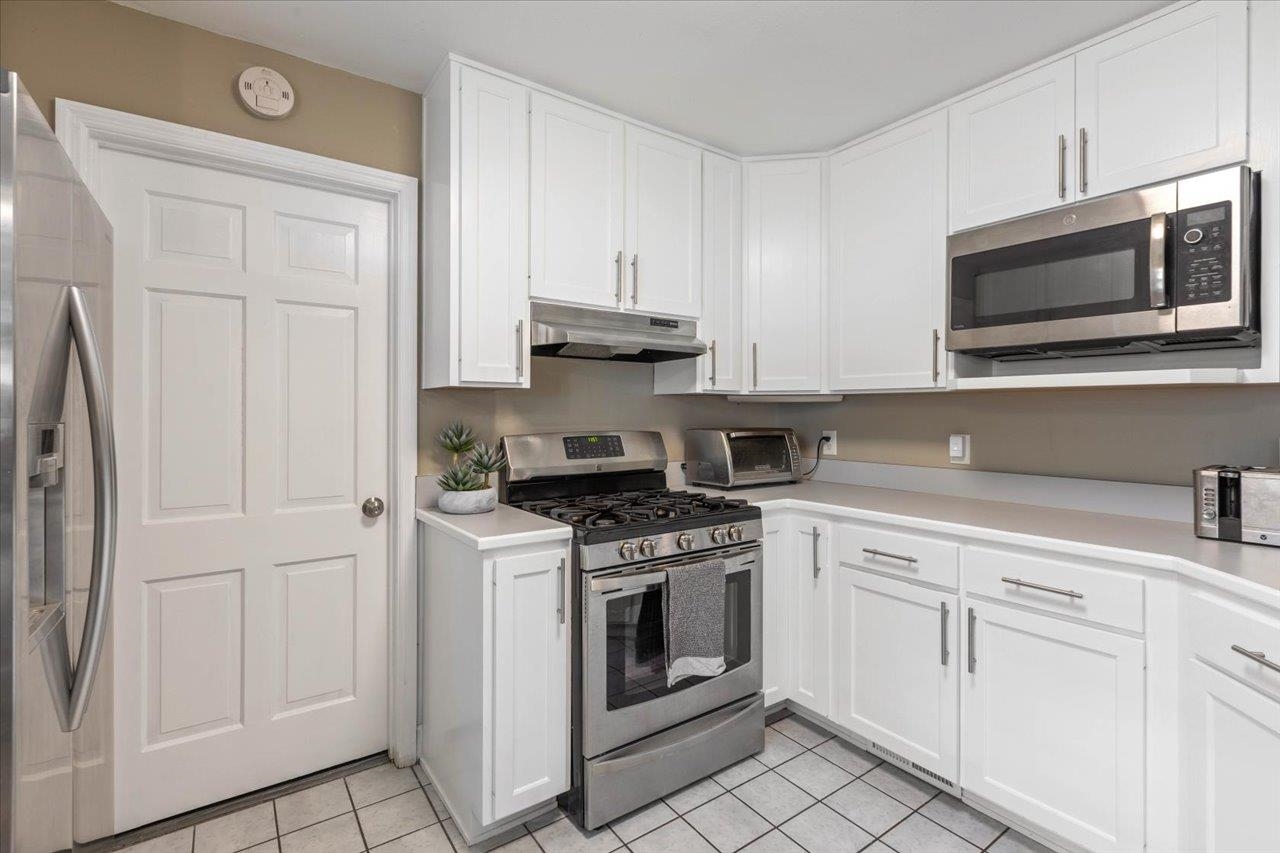Kitchen with white cabinets, stainless steel appliances, and a gas range.