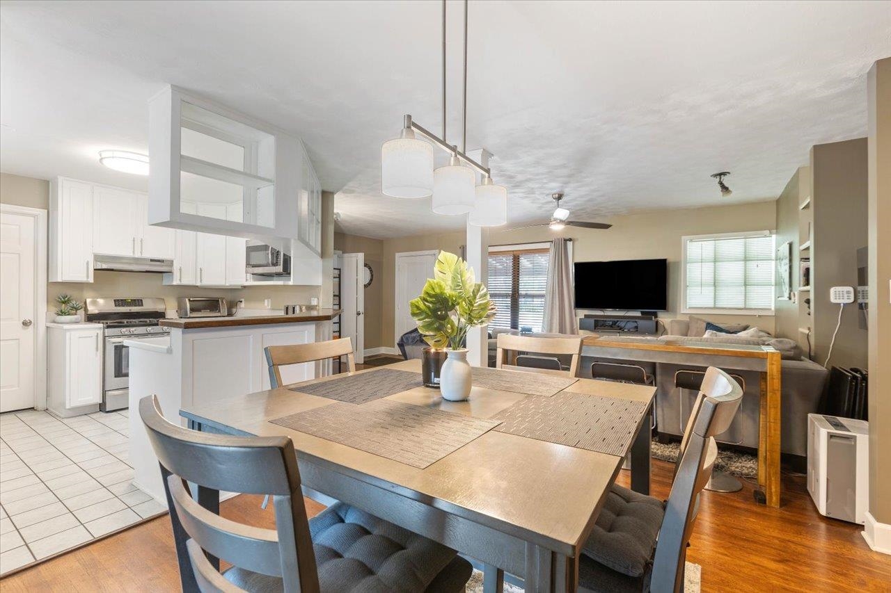 Open-plan kitchen and dining area with white cabinets and a large wood table.