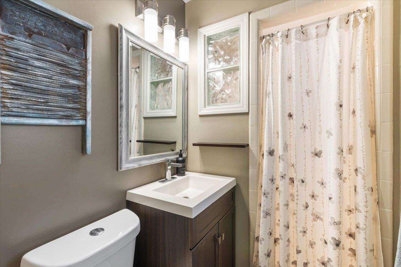 Bathroom with a dark wood vanity, framed mirror, and floral shower curtain.