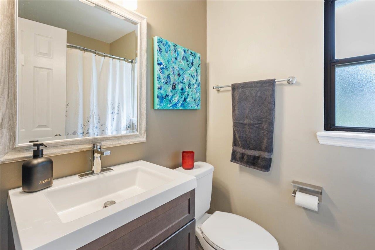 Bathroom with a dark wood vanity, white sink, large framed mirror, and toilet beside a towel bar.