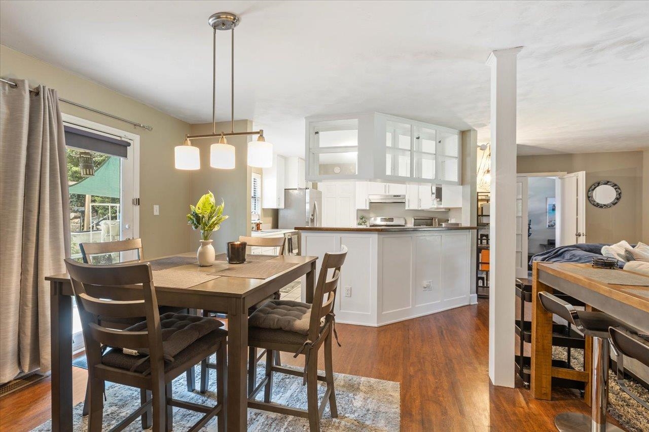 Open-plan kitchen and dining area with a white breakfast bar and wood floors.