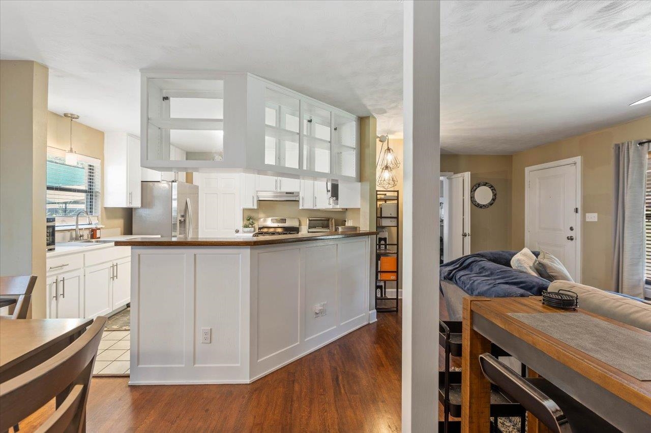 Open-plan kitchen with a large white island, glass-front cabinets, and adjoining dining and living areas.
