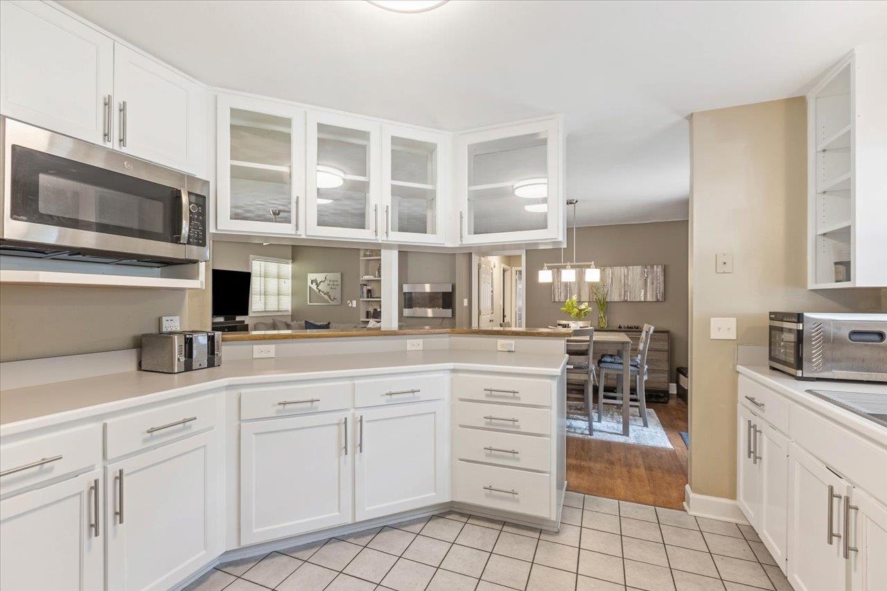 Kitchen with white cabinetry, a tiled floor, and a peninsula overlooking the dining area.
