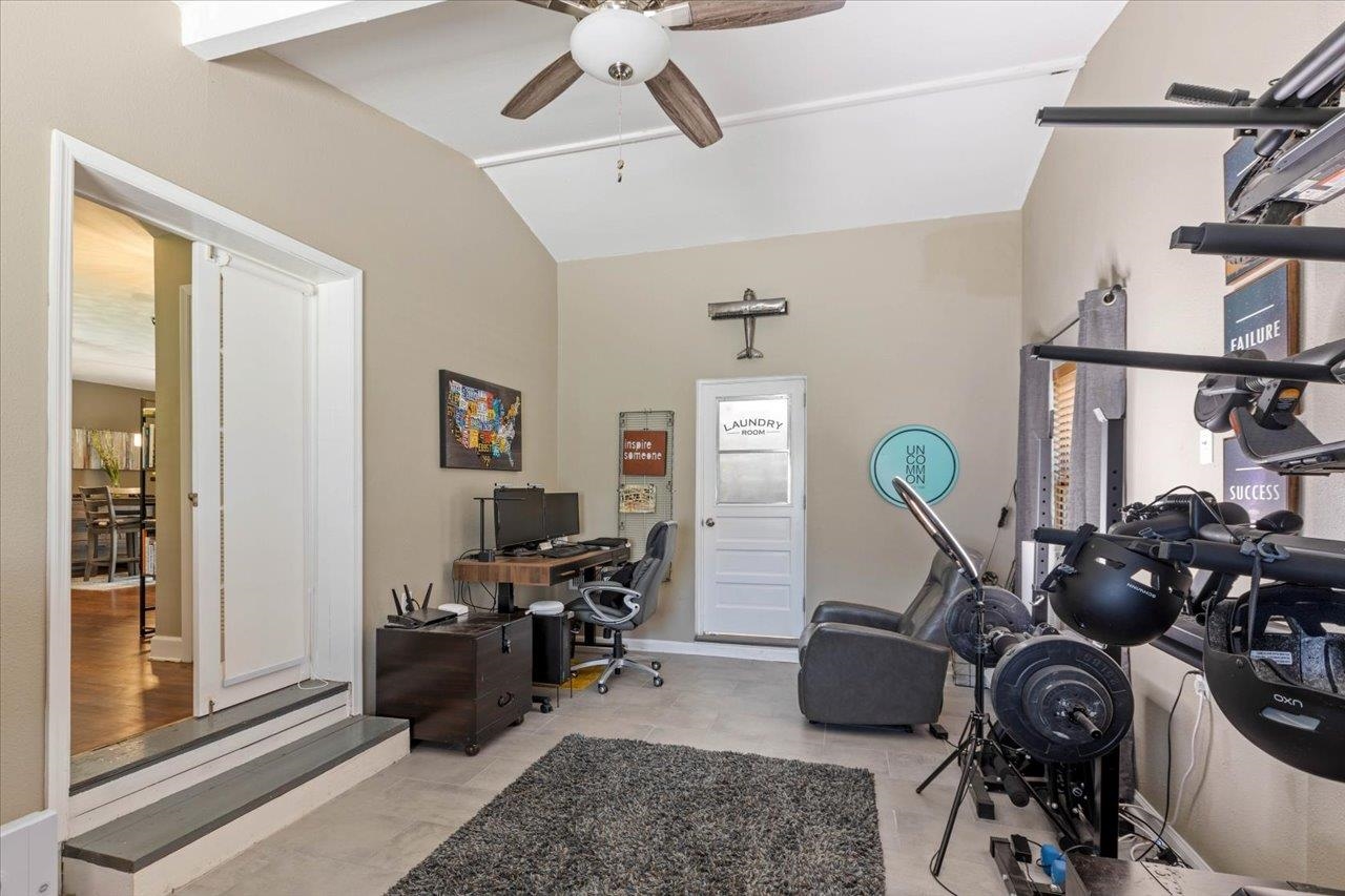 Home gym and office with workout equipment, a desk, and a laundry room door.