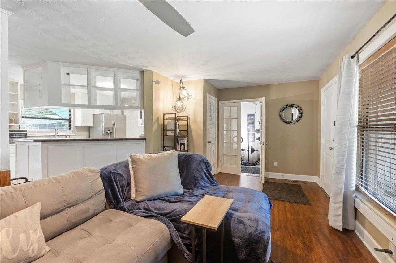 Living room with a beige sectional, blue chaise, hardwood floors, and an open kitchen.