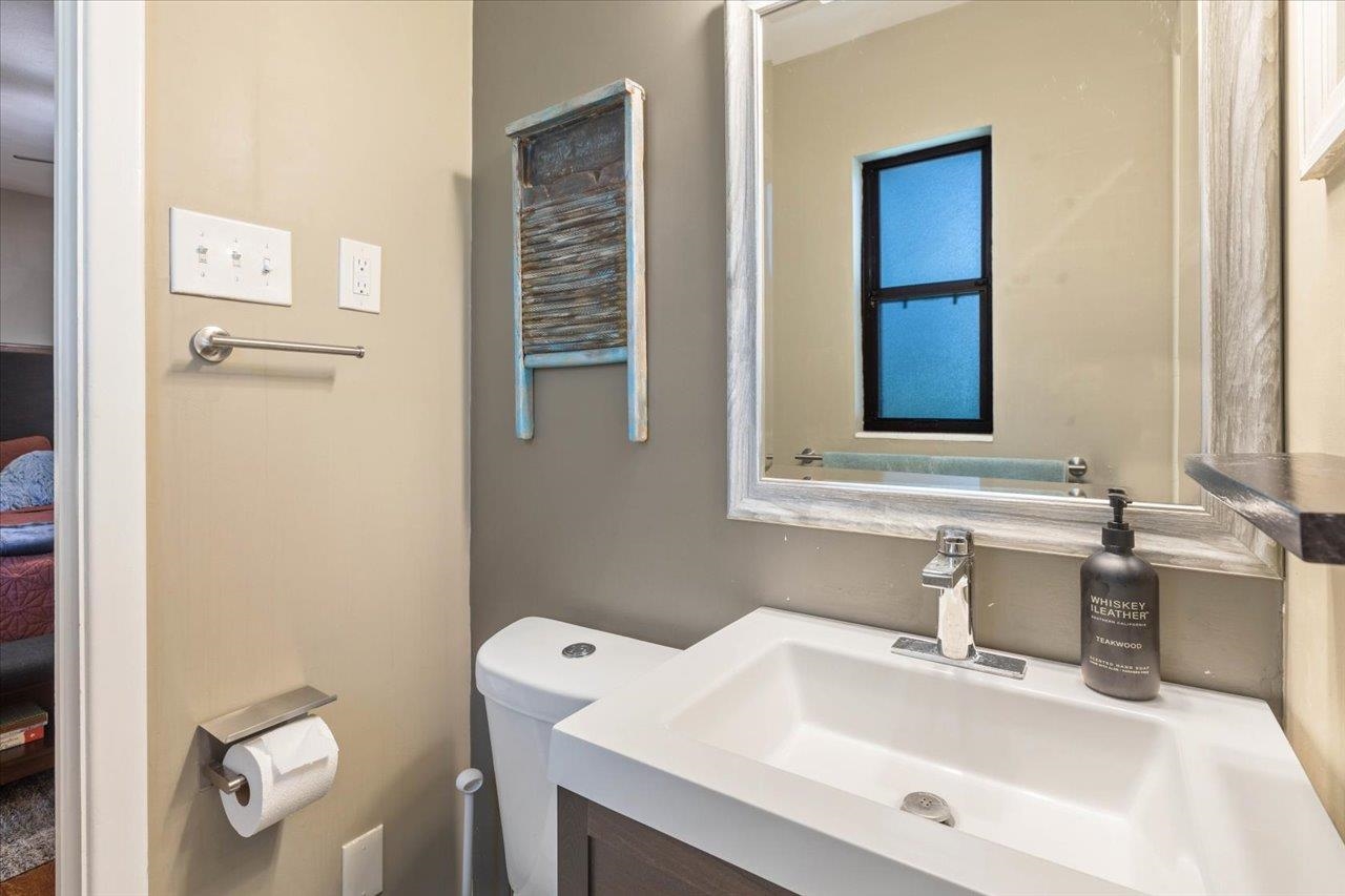 Bathroom with a white vanity sink, toilet, large mirror, and rustic wooden wall decor.