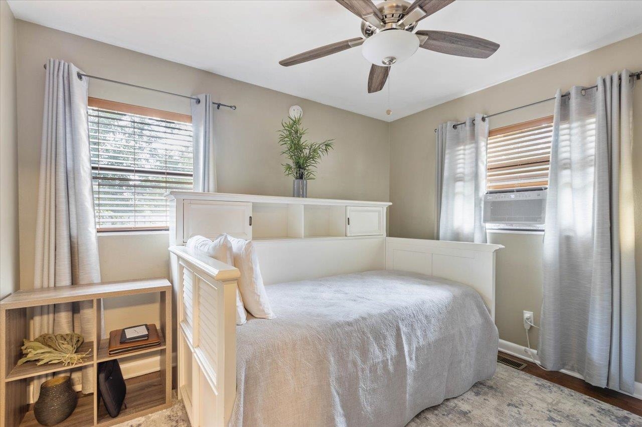 Bedroom with a white built-in bed, ceiling fan, curtained windows, and open shelving.