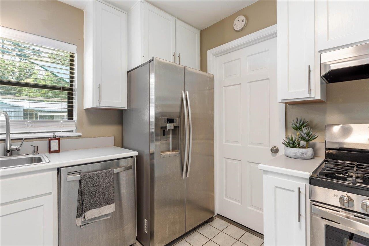 Kitchen with white cabinets, stainless steel appliances, and a sink beneath a window.