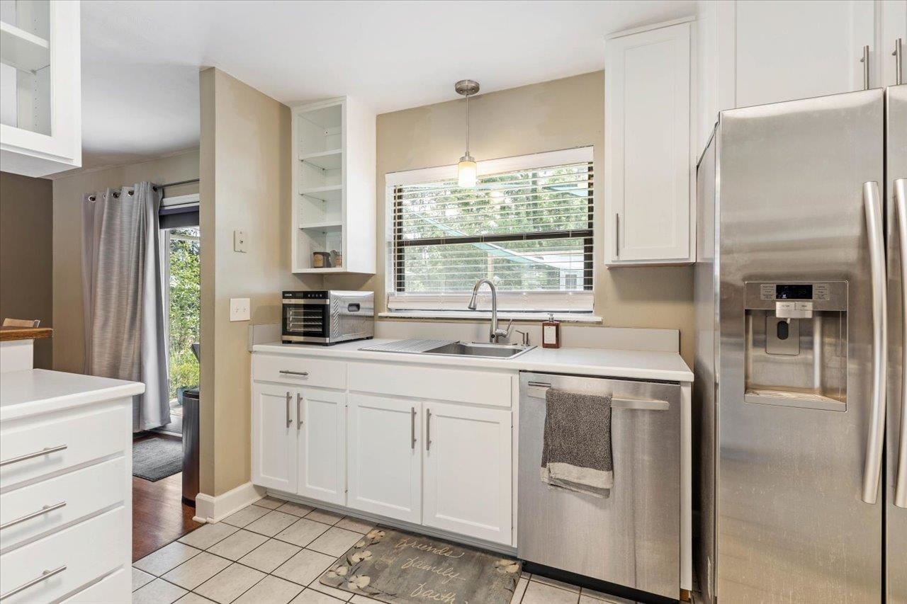 Kitchen with white cabinetry, stainless steel appliances, and a sink beneath a window.