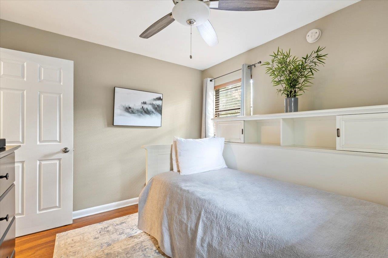 Bedroom with a single bed, built-in white storage, and a ceiling fan.