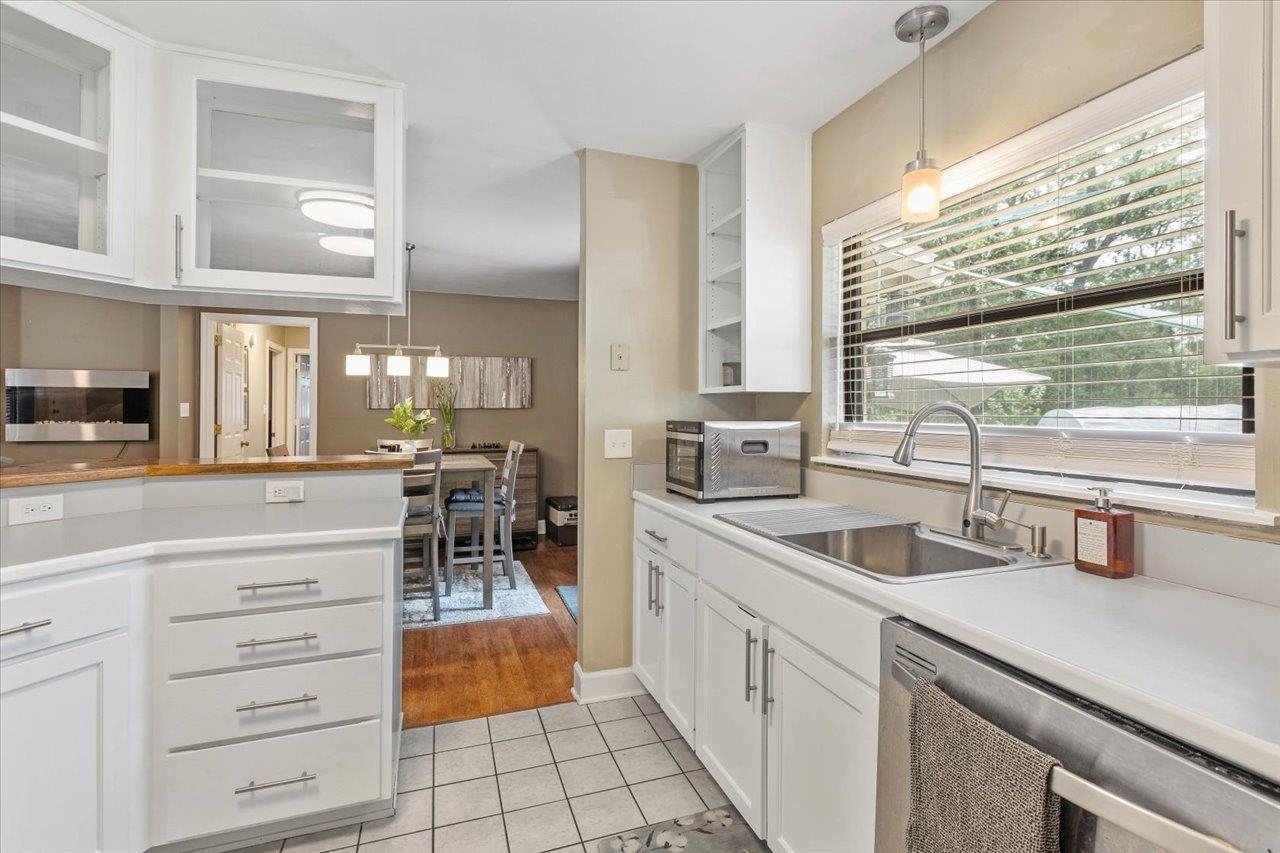 Kitchen with white cabinetry, a stainless steel sink, and a dining area beyond the breakfast bar.
