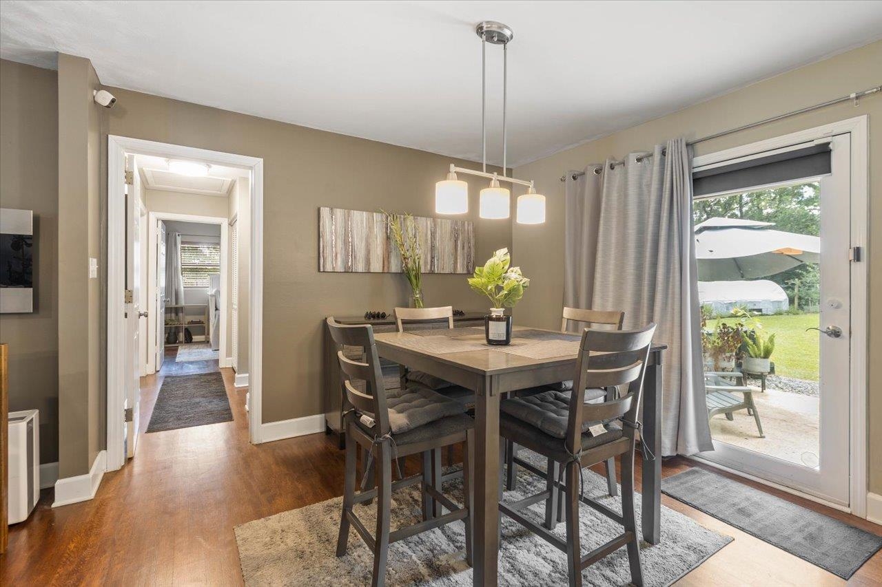 Dining room with a dark wood table, pendant light, and glass door opening to the patio.
