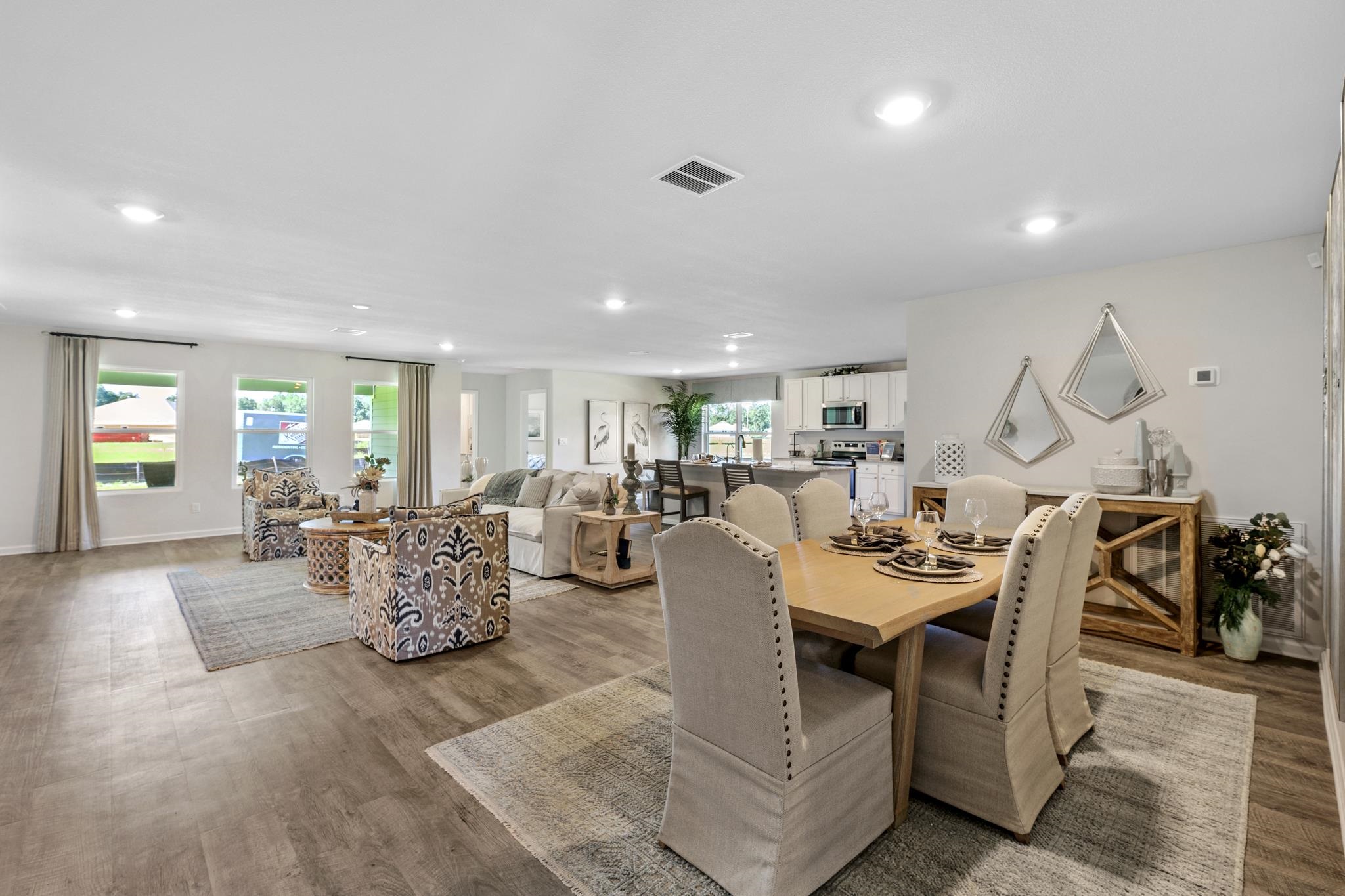 Open-plan living and dining area with a bright white kitchen and a wood dining table.
