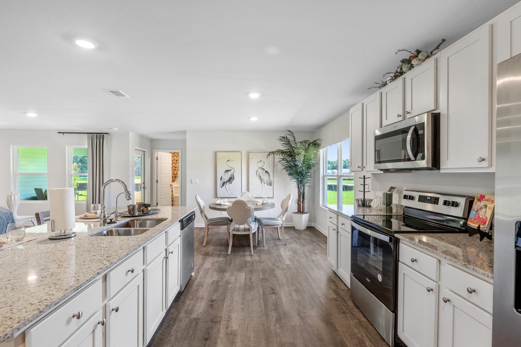 Bright kitchen with a stone island, stainless steel appliances, and an adjoining dining area.