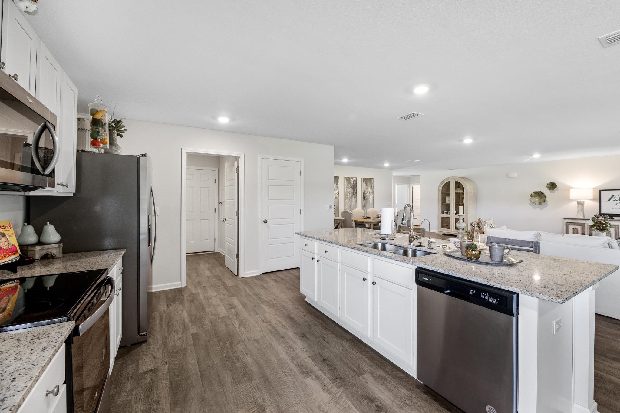 Open-plan kitchen with white cabinets, stainless steel appliances, and a large island overlooking the living area.