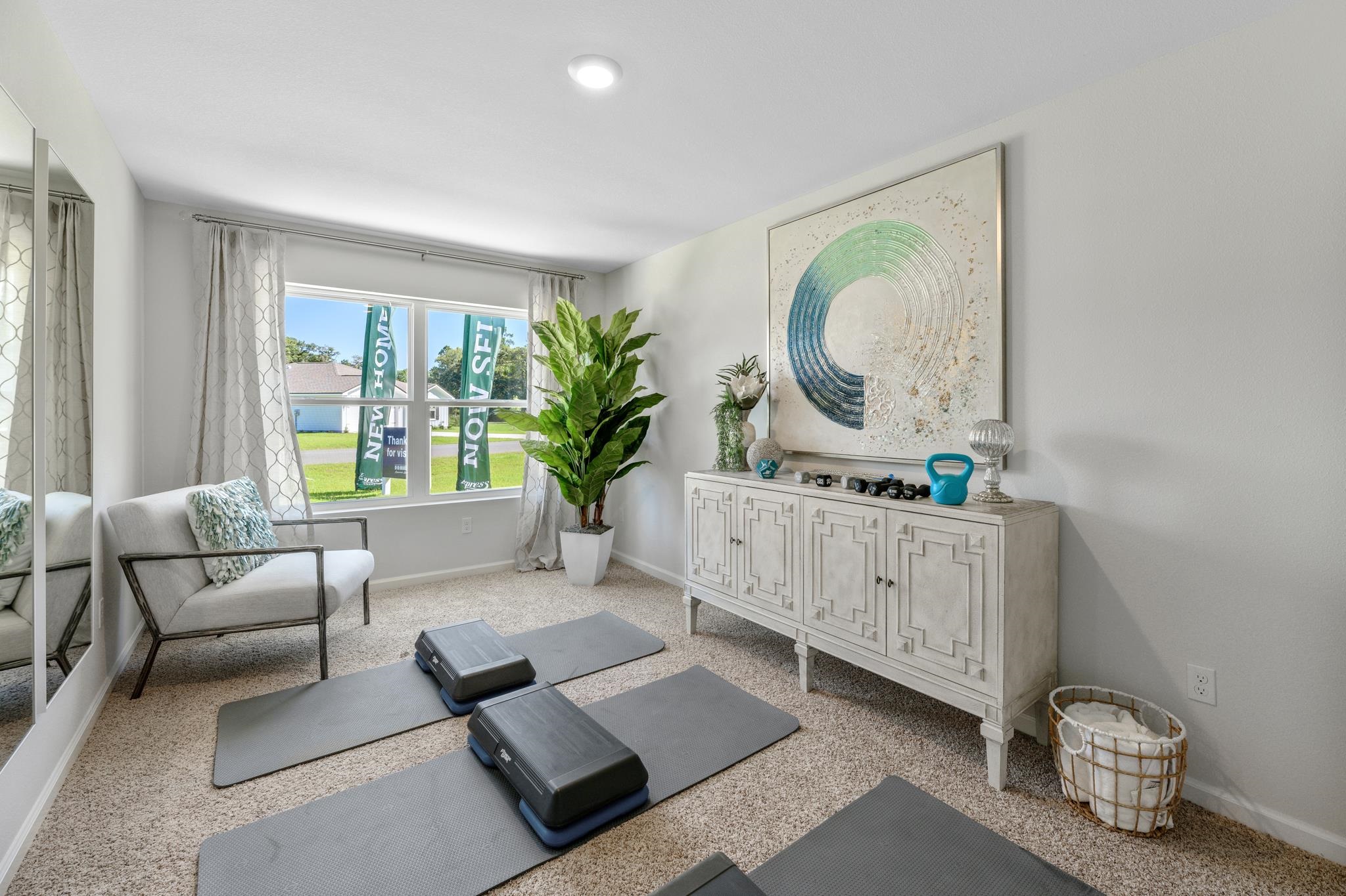 Furnished exercise room with gray workout mats, step platforms, and a large window.