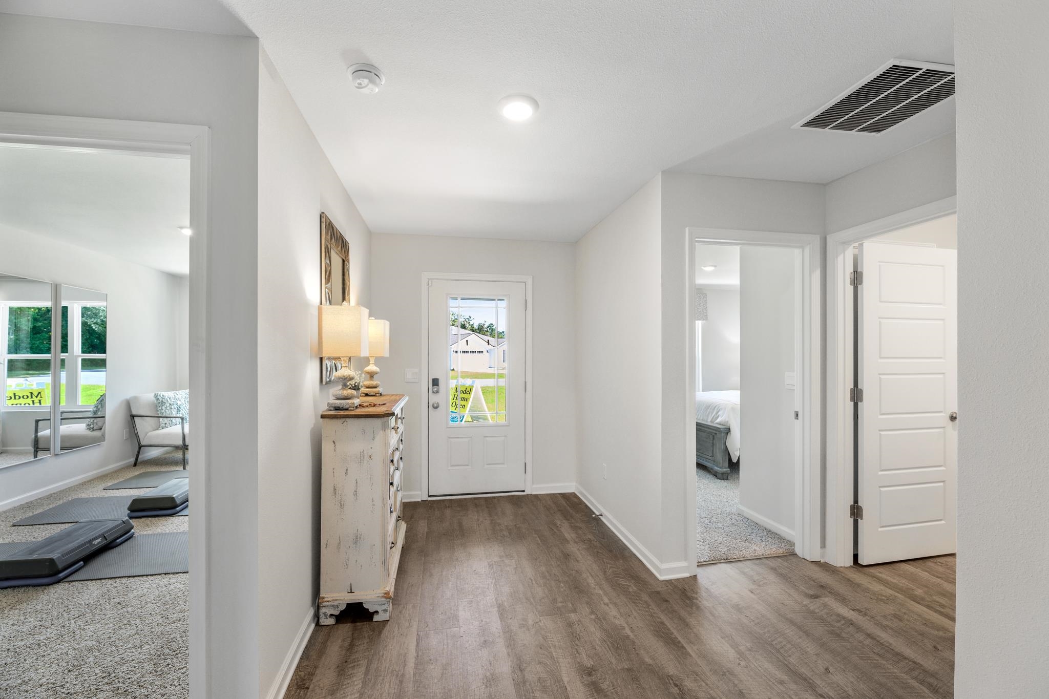Entry hall with a glass-paneled front door, distressed console cabinet, and open doorways to adjoining rooms.