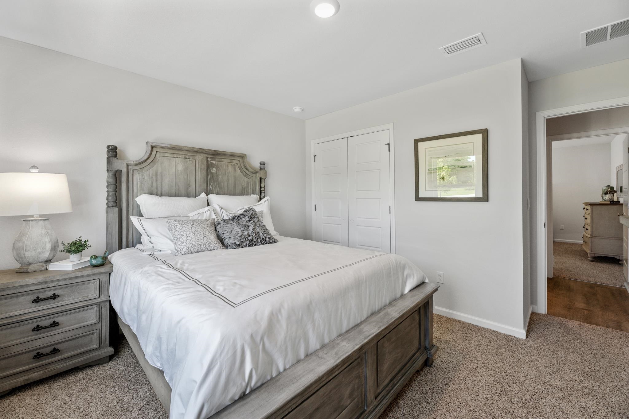 Bedroom with a large gray wood bed, white bedding, and a doorway to an adjoining room.