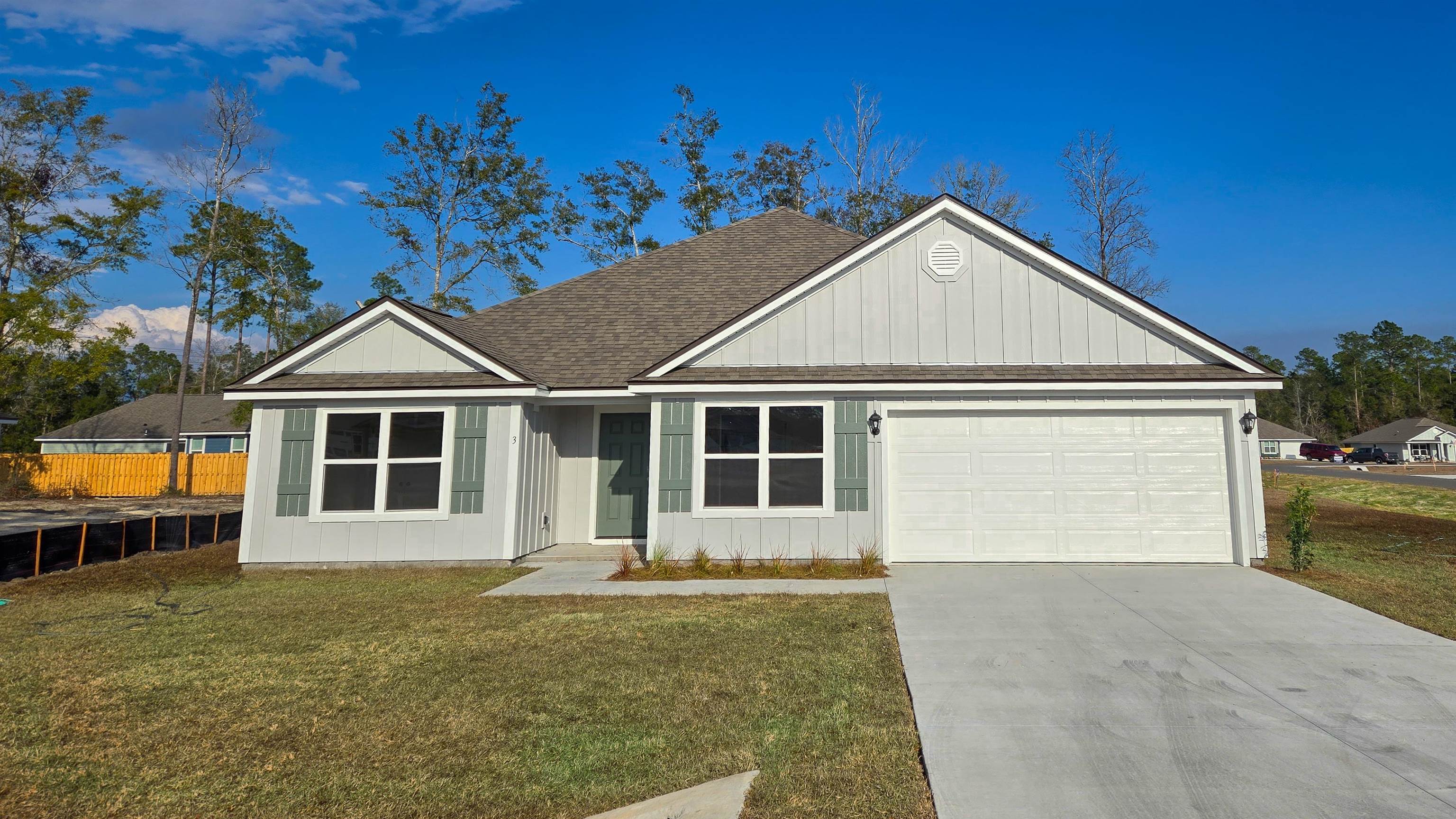 Light gray single-story home with sage shutters, covered entry, and attached two-car garage.