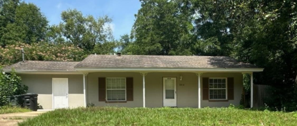 Single-story house with a covered porch, two white doors, and a grassy yard.