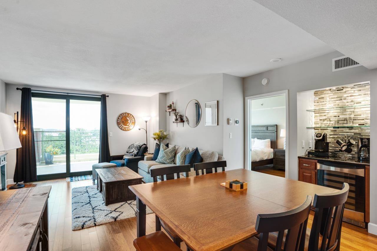 Condo living and dining area with a wooden table and sliding doors opening to a balcony.