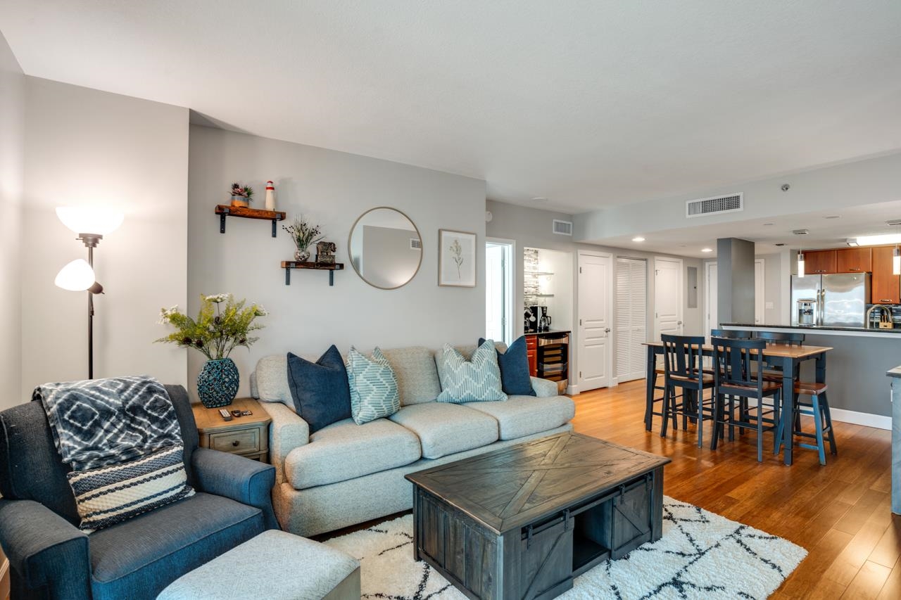 Open-plan living and dining area with a light sectional, wood coffee table, and bar-height dining set.