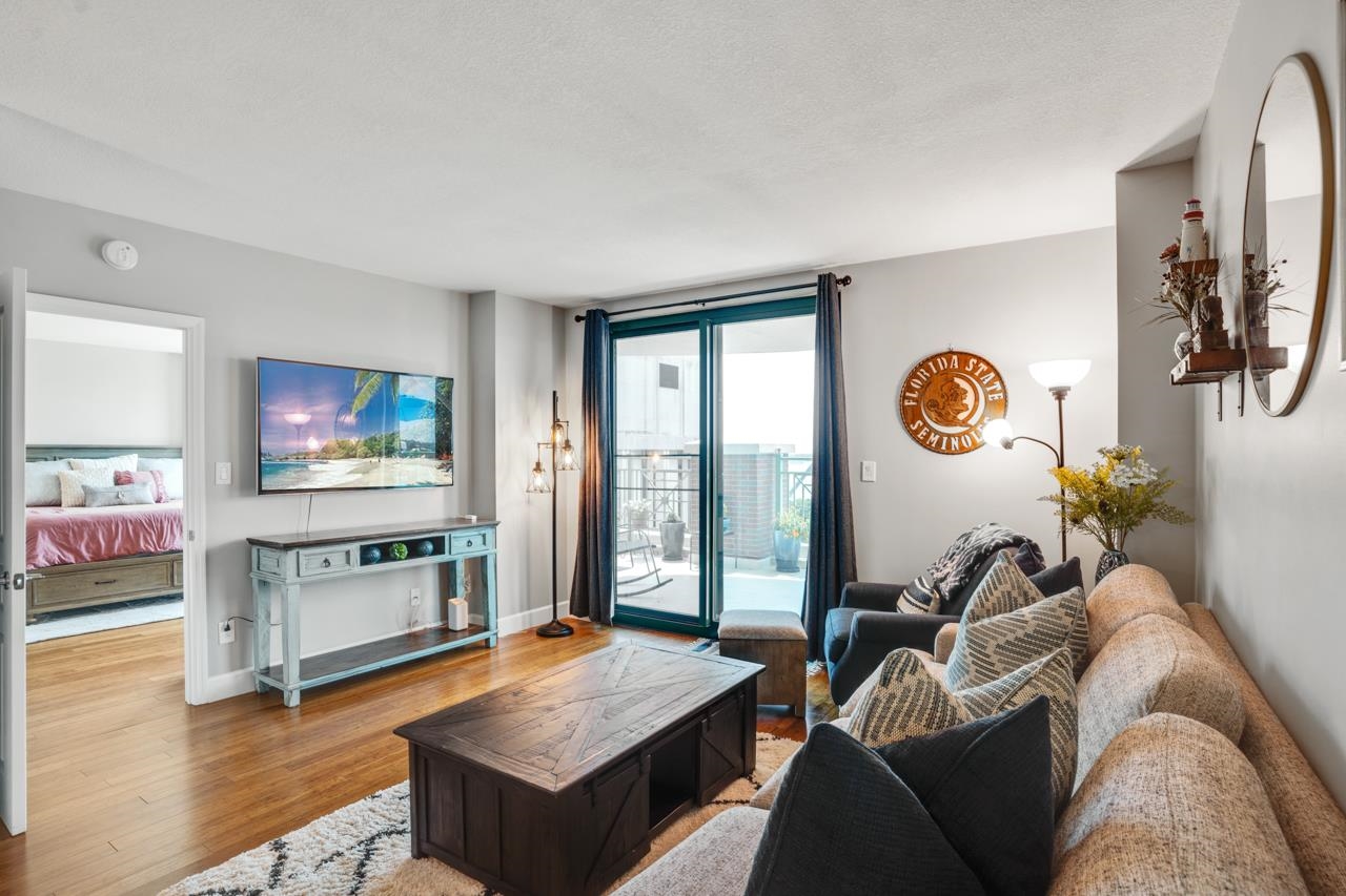 Condominium living room with patterned sofas, a dark wood coffee table, and sliding glass doors to a balcony.