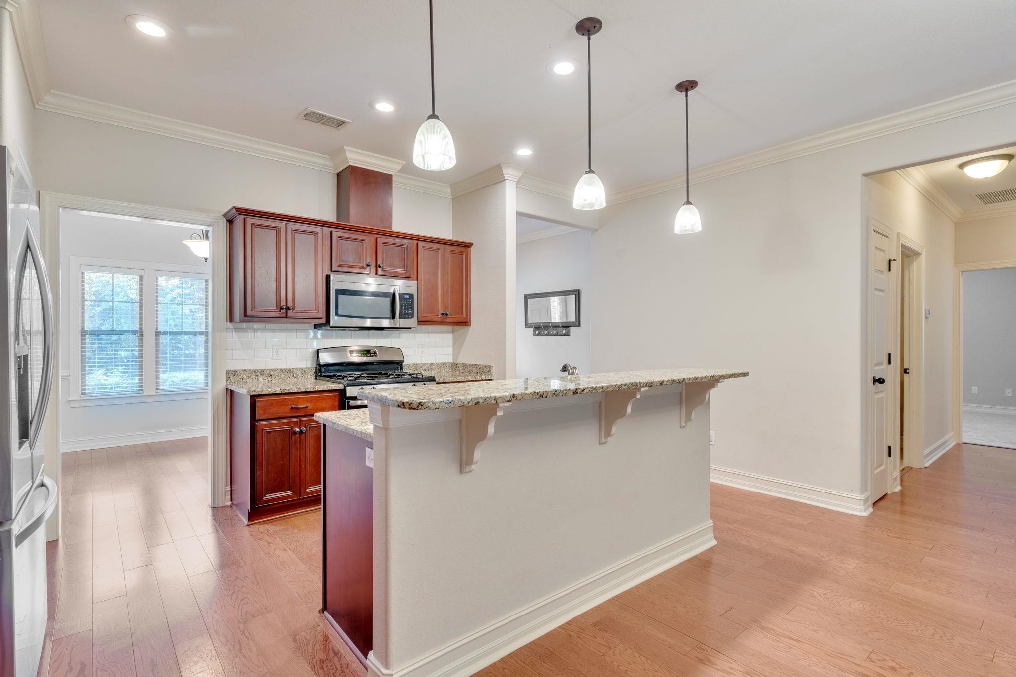 Kitchen with cherry cabinets, stainless steel appliances, granite counters, and a long breakfast bar.