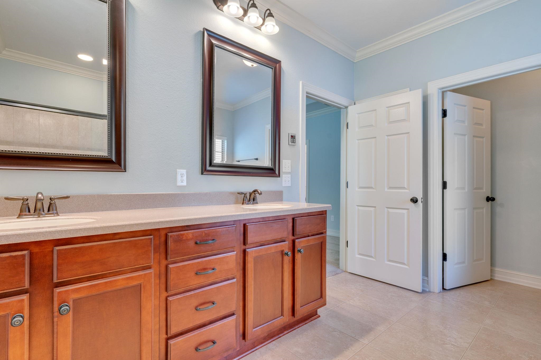 Bathroom with a double-sink wood vanity, pale countertop, and framed mirrors.