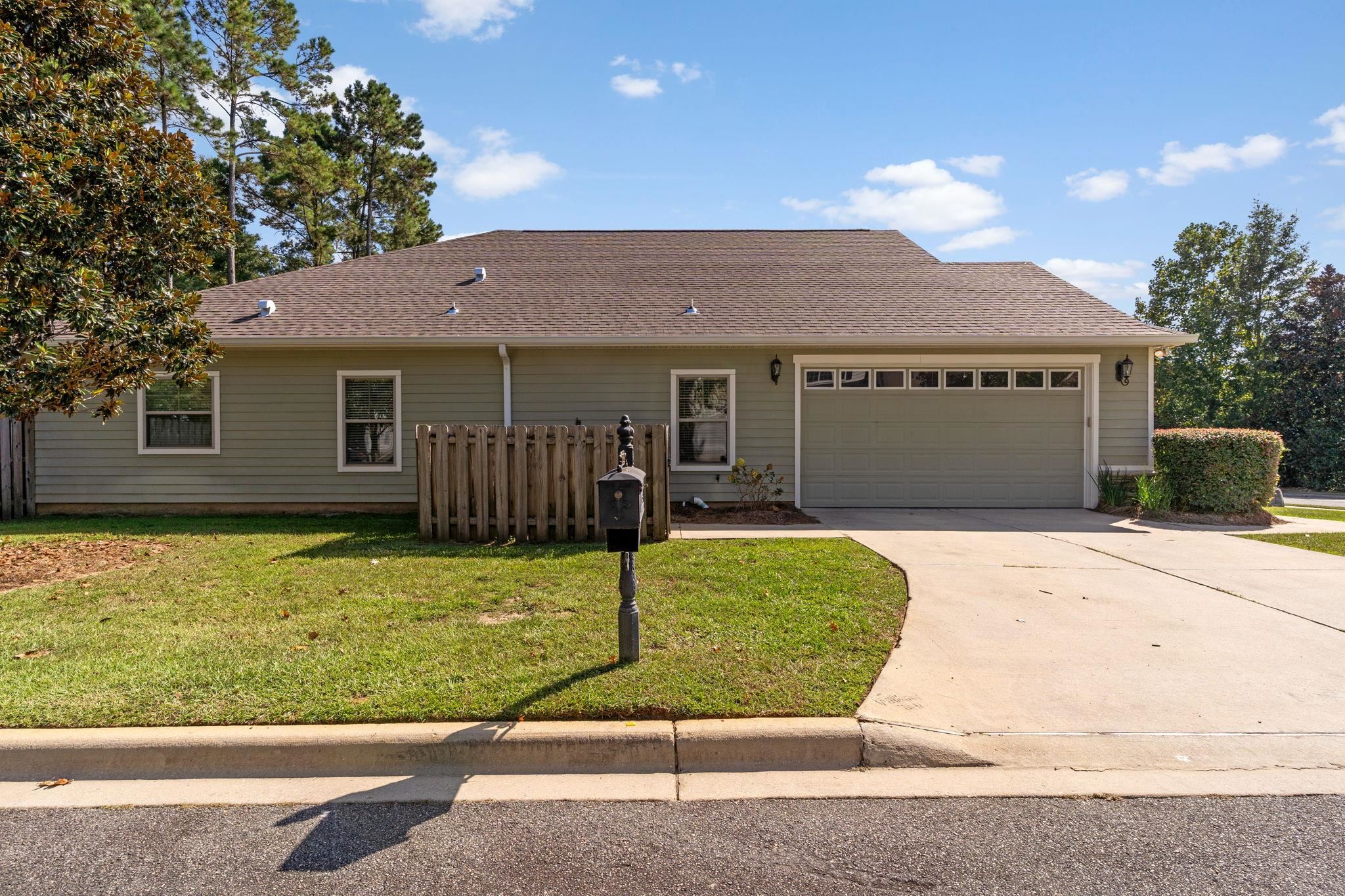Single-story house with an attached garage, curved driveway, front lawn, and mailbox.