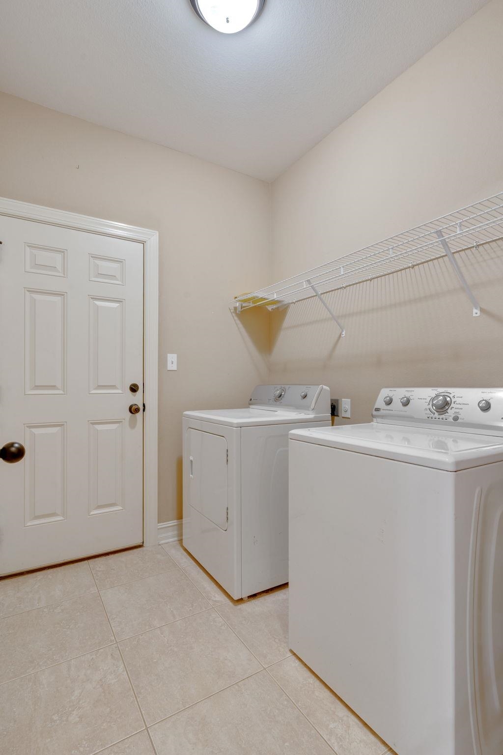 Laundry room with a washer and dryer beneath wire shelving.