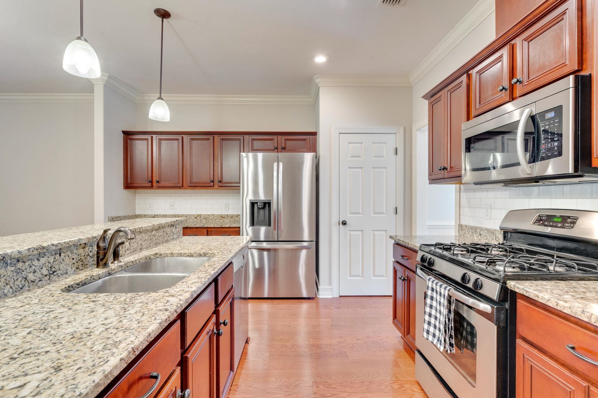 Kitchen with reddish-brown cabinets, granite counters, and stainless steel appliances.