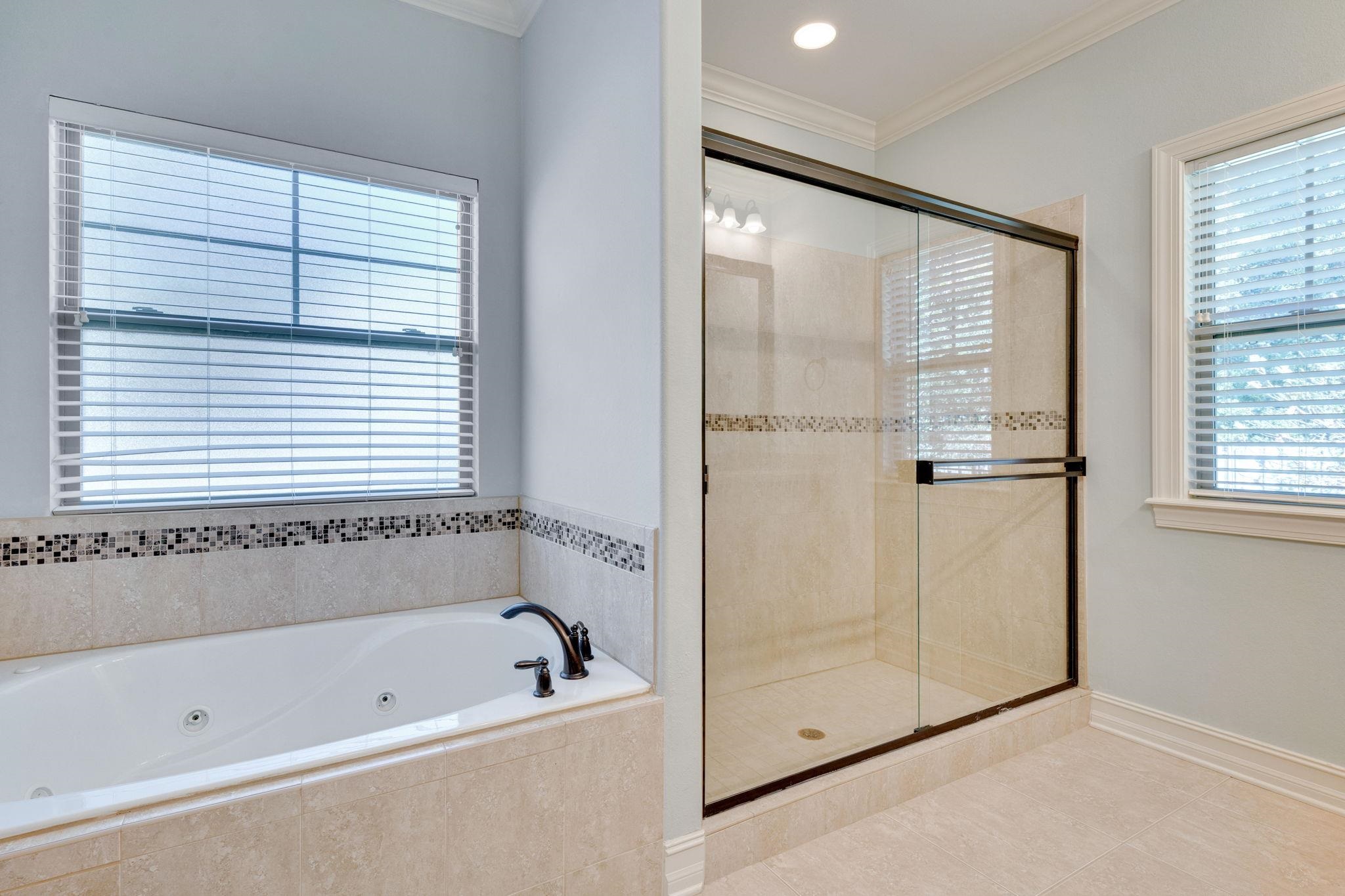 Bathroom with a jetted tub beside a glass-enclosed walk-in shower.