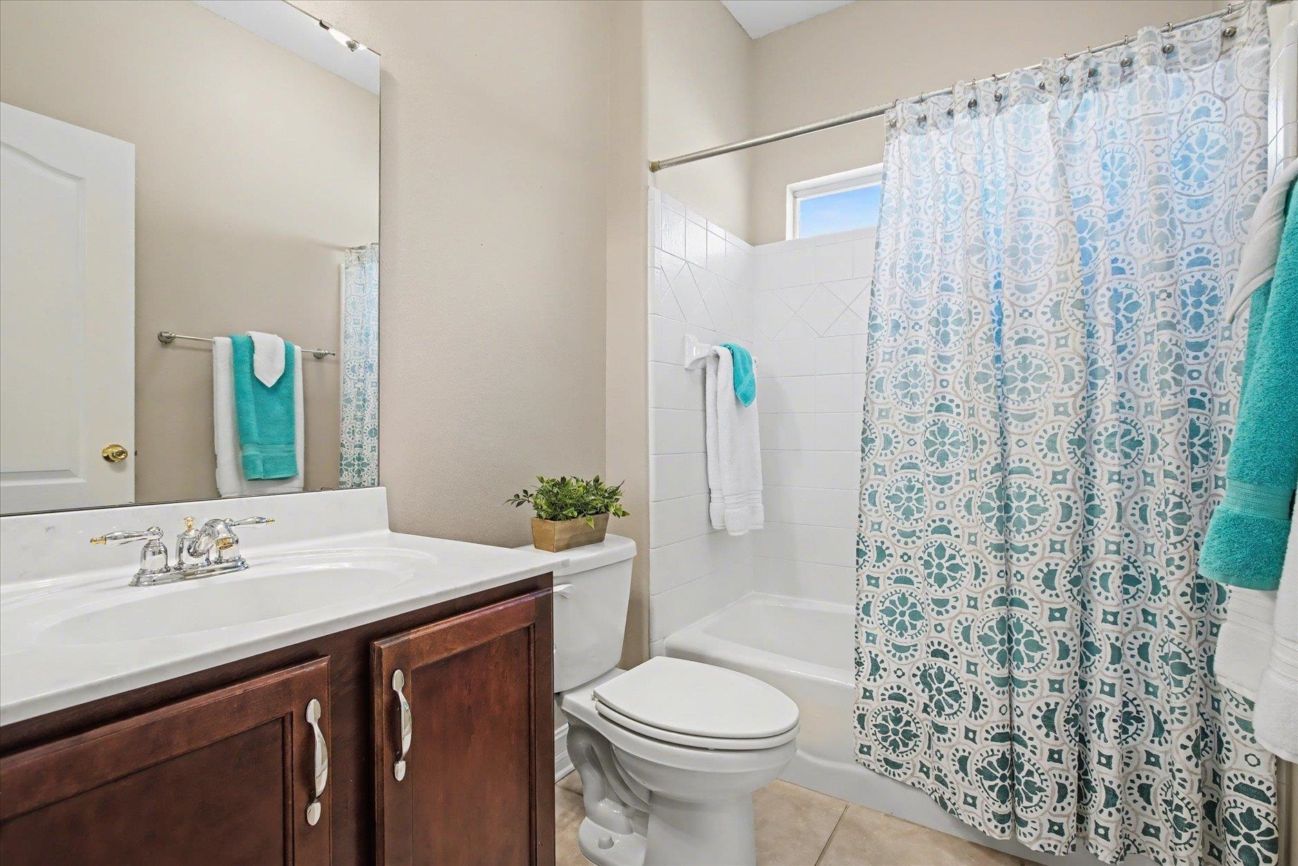 Bathroom with a dark wood vanity and a blue-and-teal patterned shower curtain.