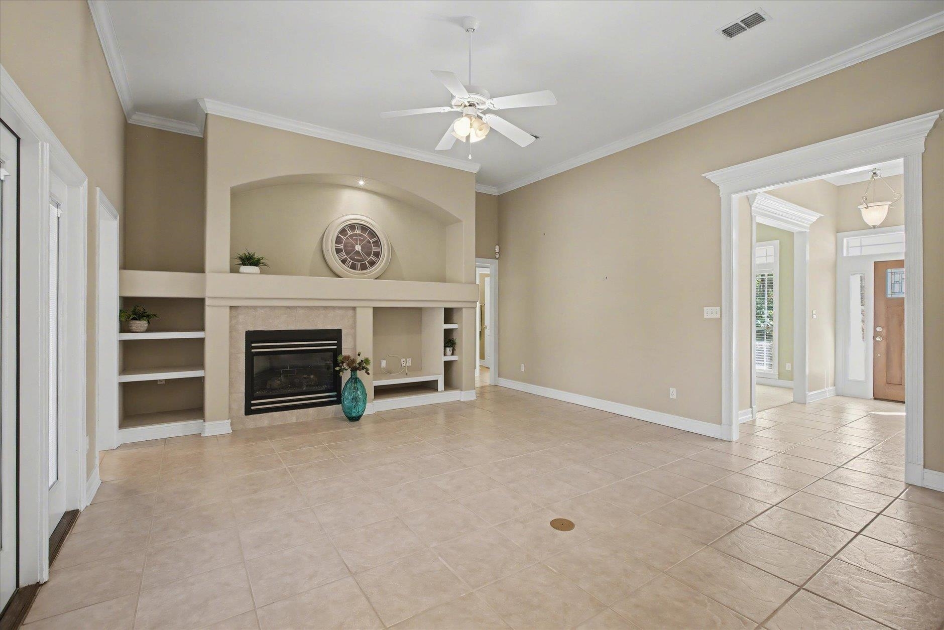 Living room with a built-in fireplace, tiled floor, and arched alcove with a clock.