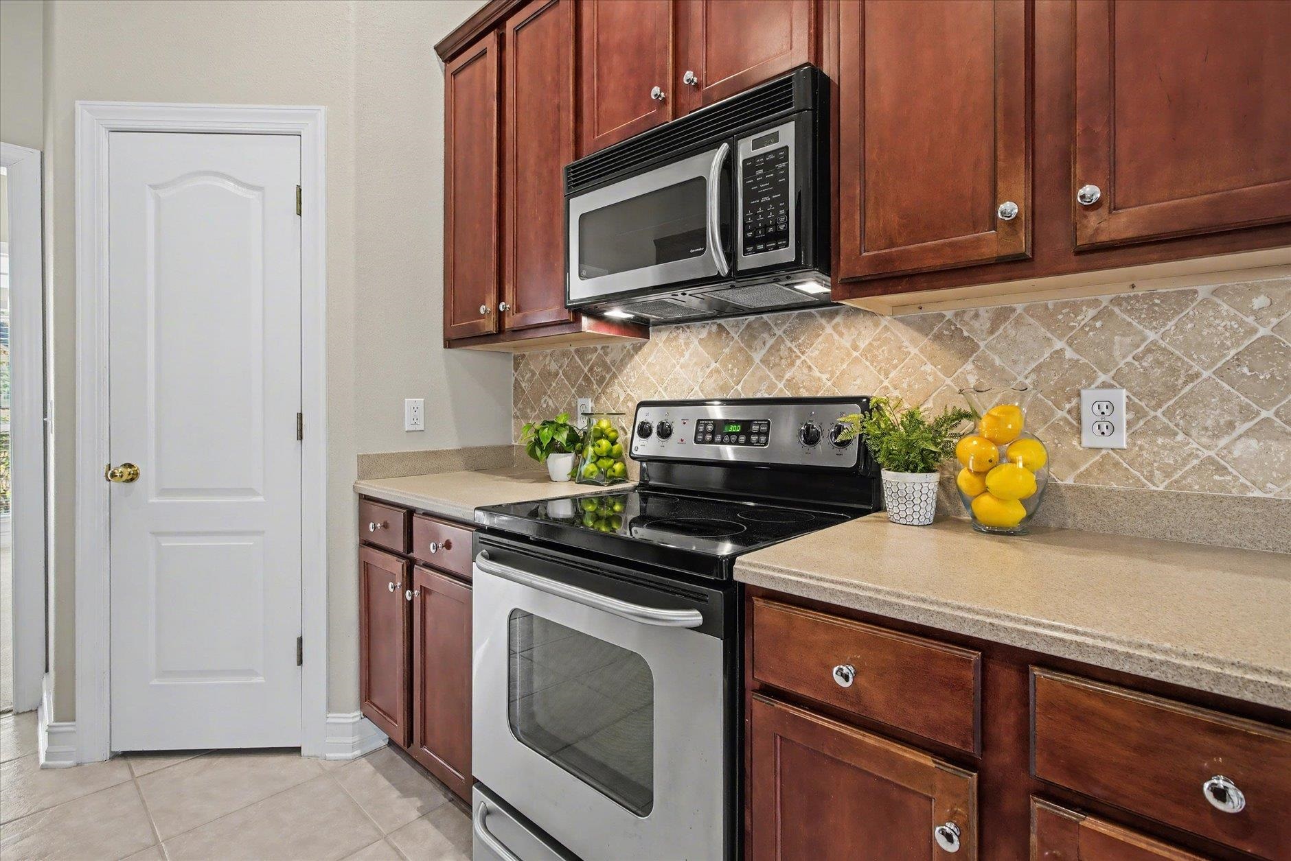 Kitchen with wood cabinetry, stainless steel appliances, and a diamond-pattern tile backsplash.