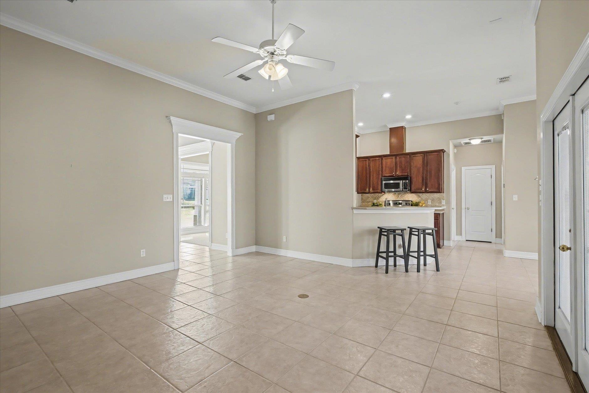 Tiled dining area opening to a kitchen with dark wood cabinets and a breakfast bar.