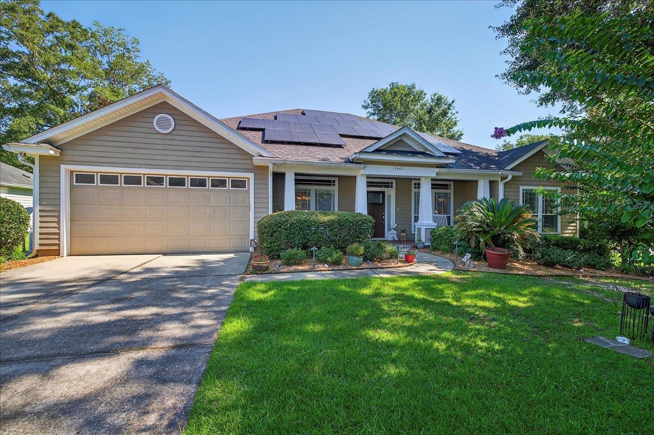 Gray single-story home with rooftop solar panels, a two-car garage, and a covered front porch.